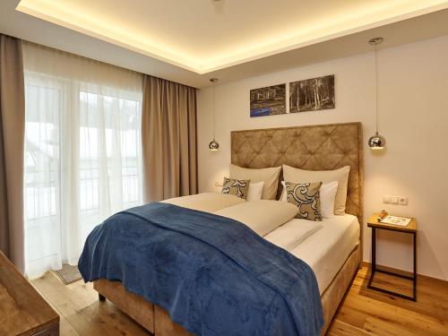 a bedroom with a large bed with a blue blanket on it at A-VITA Viktoria & A-VITA living luxury apartments in Seefeld in Tirol