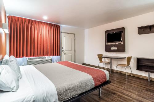 a hotel room with a bed and a tv at Pacific Inn in Oceanside