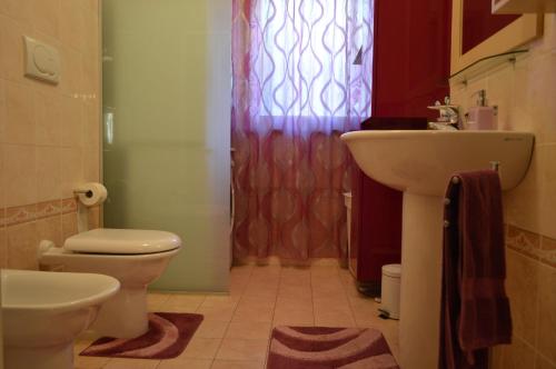 Un baño con lavabo, inodoro y ventana. en La Casa di Manolo, en Bolonia