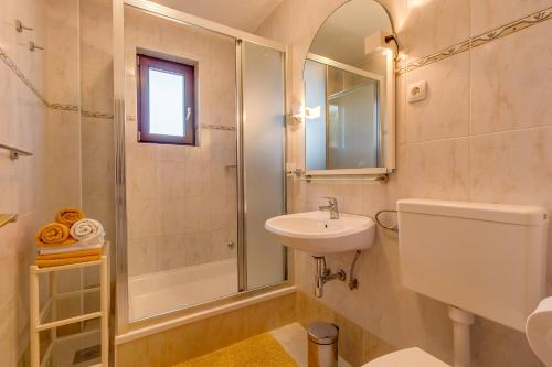 ein weißes Bad mit einem Waschbecken und einer Dusche in der Unterkunft Vlasta in Mali Lošinj