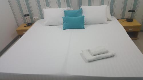 a white bed with blue and white pillows on it at Apto T1 Comfort in Praia