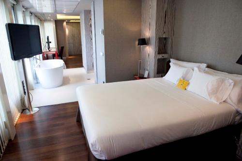 a bedroom with a large white bed and a television at Hotel Alfonso in Zaragoza