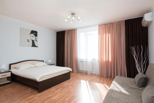 a bedroom with a bed and a couch at Apartment Tatiana in Yekaterinburg