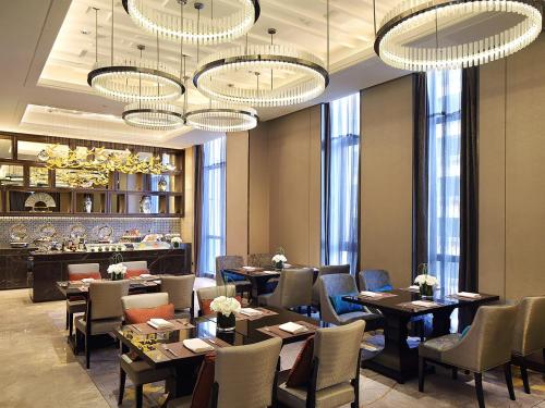 a restaurant with tables and chairs and chandeliers at Wanda Realm Neijiang in Neijiang