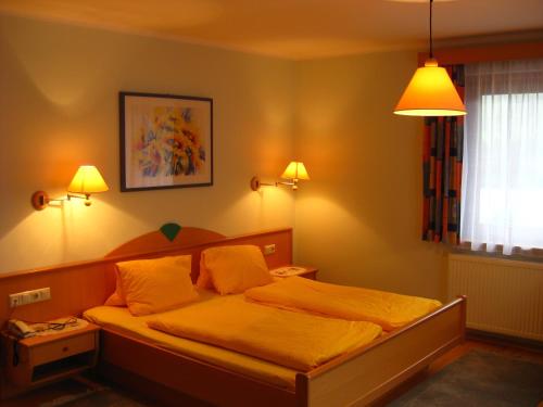 ein Schlafzimmer mit einem Bett mit gelber Bettwäsche und zwei Lampen in der Unterkunft Pension Bräuhaus in Bad Kleinkirchheim