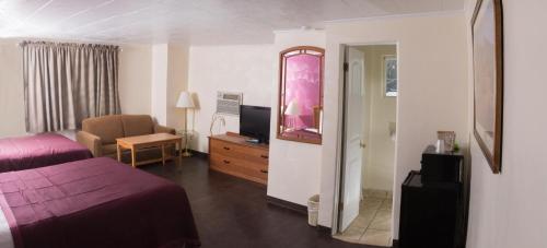 a hotel room with a bedroom with a bed and a tv at Budget Inn in Caldwell