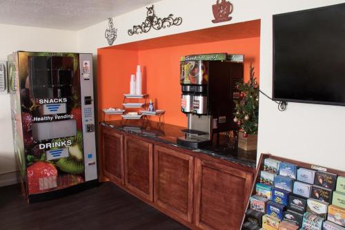 a coffee shop with an orange wall and a tv at Budget Inn in Caldwell