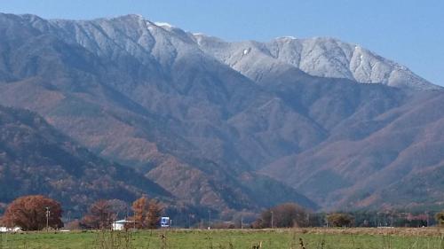 a mountain range with snow covered mountains in a field at Hotel Ina in Ina