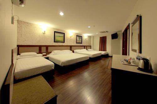 a hotel room with three beds and a table at Ming Paragon Hotel in Kuala Terengganu