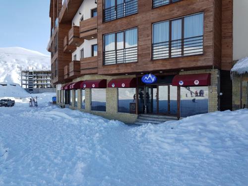 a building with a pile of snow in front of it at New Gudauri Sunny studio in Gudauri