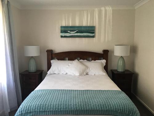 a bedroom with a bed with two lamps on tables at Victoria Road B&B in Mount Maunganui