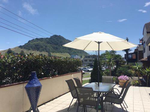 een tafel en stoelen met een parasol op een patio bij Victoria Road B&B in Mount Maunganui
