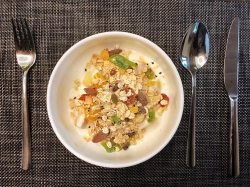 a white bowl of food with vegetables on a table with silverware at Rock&Wood Cozy House in Hangzhou
