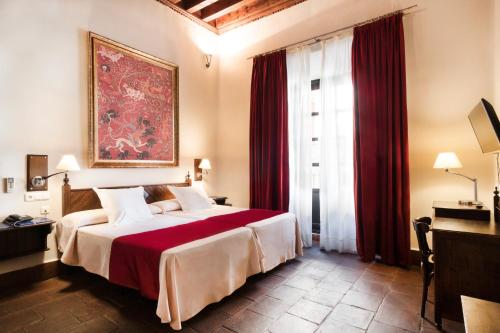 a bedroom with a large bed with red curtains at Casa Palacio Pilar del Toro in Granada