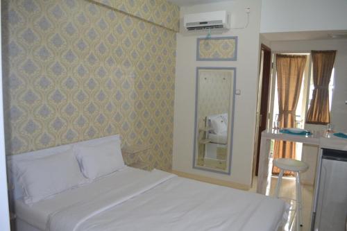 Schlafzimmer mit einem weißen Bett und einem Spiegel in der Unterkunft Green Lake View - Tower E 59 Acuan Laundry Time in Pondokcabe Hilir
