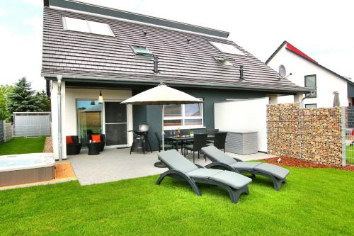 a patio with a table and chairs and an umbrella at Ferien_VILLA EASY LIVING in Göhren-Lebbin