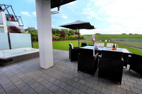 eine Terrasse mit einem Tisch, einem Sonnenschirm und einer Badewanne in der Unterkunft Ferien-VILLA PACE in Göhren-Lebbin