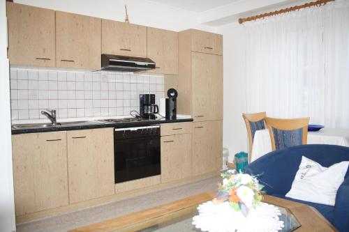 a kitchen with wooden cabinets and a sink and a table at Pension / Ferienwohnung Allebrodt in Lennestadt