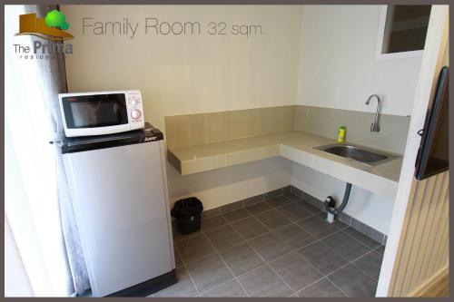 a small kitchen with a microwave on top of a refrigerator at The Prima Residence - SHA Certificate in Bangkok