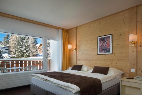 a bedroom with a bed and a large window at Hotel La Prairie in Crans-Montana
