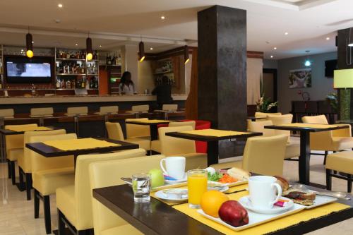 un restaurante con mesas y sillas con comida. en Hotel VDN by Good Rade en Dakar