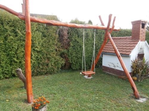 a swing in a yard with a house at Nádkunyhó Vendégház in Hegyhátszentjakab