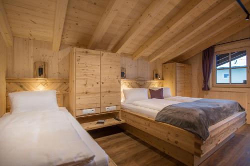 two beds in a room with wooden walls at Alpenchalet Stadlpoint in Ried im Zillertal