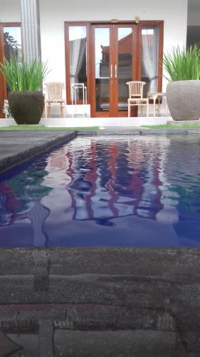 a swimming pool with a reflection in the water at Sanata Yoga Guesthouse in Canggu