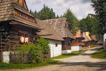 an old log house with a white garage next to a street at Apartment Skurčák in Zuberec