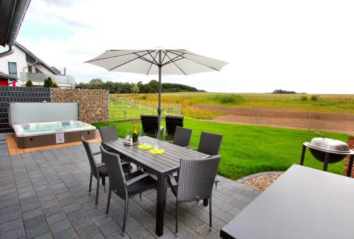 a patio with a table and chairs and an umbrella at Ferien_VILLA SANSIBAR in Göhren-Lebbin