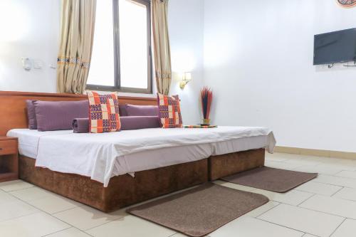 a bed with pillows on it in a room at Asantewaa Premier Hotel in Kumasi