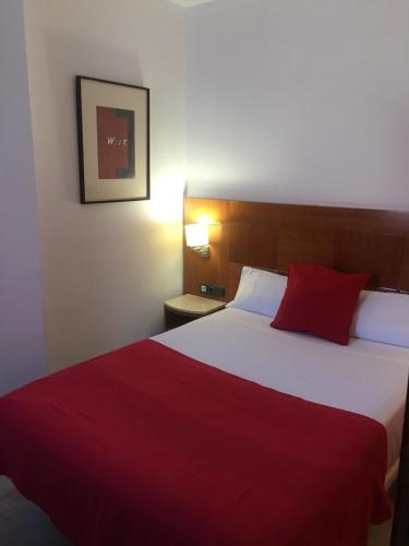 a hotel room with a large bed with a red blanket at Hotel Calasanz in Molins de Rei
