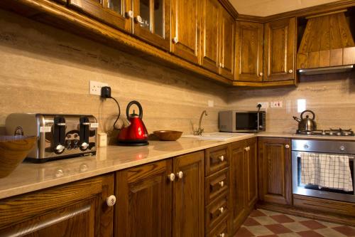 a kitchen with wooden cabinets and a red appliance on the counter at Maltese Town House Sliema in Sliema
