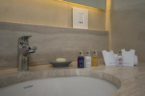 a bathroom sink with bottles ofodorizers on a counter at Ocean Vista Boutique Guest House in Durban