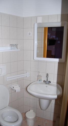 a bathroom with a sink and a toilet and a mirror at Judit Panzio in Gyulakeszi