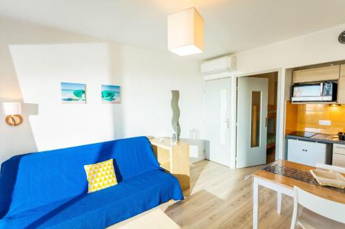 a living room with a blue couch and a table at Résidence de Tourisme l'Albatros in Palavas-les-Flots