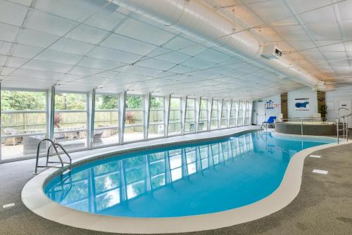 a large indoor swimming pool with blue water and windows at George Hotel in Hexham