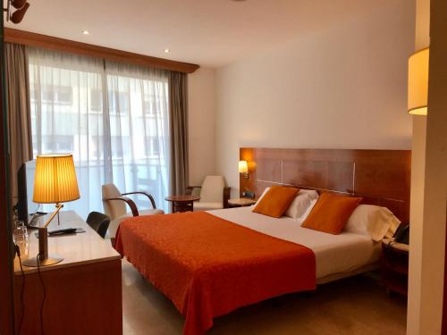 une chambre d'hôtel avec un lit et un bureau avec une lampe dans l'établissement Hotel Calasanz, à Molins de Rei