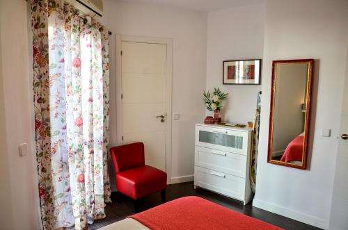 een slaapkamer met een rode stoel en een spiegel bij AlohaMundi Campana in Sevilla