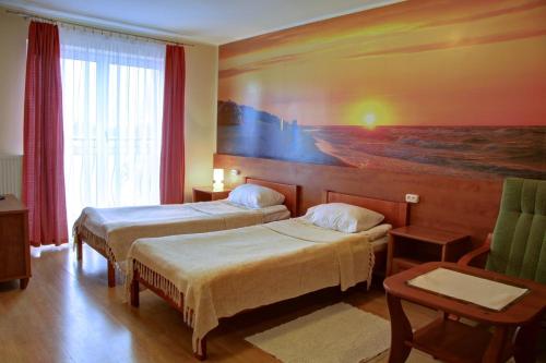 una camera d'albergo con due letti e un dipinto sul muro di Apartamenty & Restauracja Janus a Ełk