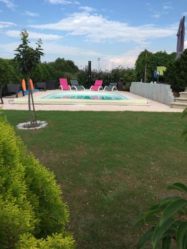 a swimming pool with pink chairs in a yard at Maison privée in Kingersheim