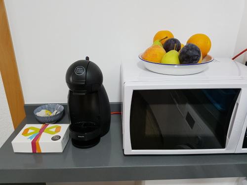 a coffee maker and a bowl of fruit on a microwave at Apartamento centrico in Almuñécar