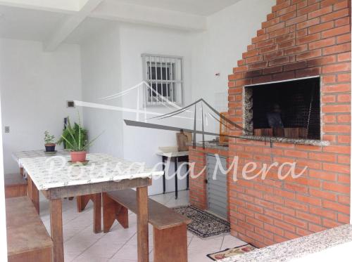 a living room with a brick fireplace and a table at Pousada Mera in Florianópolis