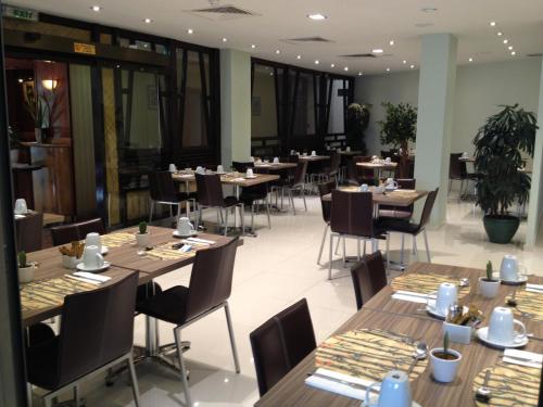 ein Restaurant mit Holztischen und -stühlen und Fenstern in der Unterkunft Castelli Hotel Nicosia in Nikosia