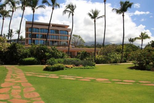 a large building with palm trees in front of a yard at Maui KaanapaliVilla A517 in Lahaina