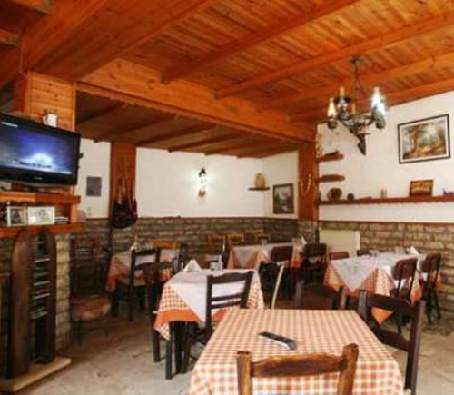 a restaurant with tables and chairs and a flat screen tv at Lithos in Sirmbáni
