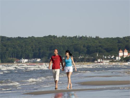 a man and a woman walking on the beach at Dorint Seehotel Binz-Therme in Binz