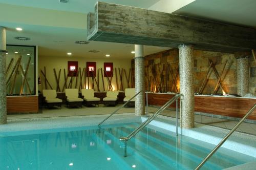 a swimming pool in a hotel with chairs and tables at Hospes Palacio de Arenales & Spa in Cáceres