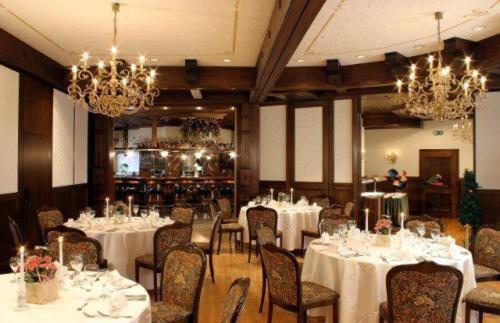 a dining room with white tables and chairs and chandeliers at Landhotel Lippischer Hof in Lügde