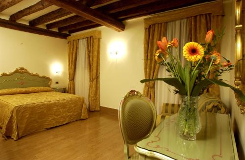 a bedroom with a vase of flowers on a table at Hotel Al Ponte Mocenigo in Venice